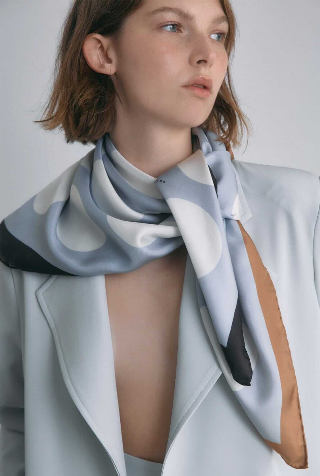 Stylish woman wearing a patterned scarf as part of her outfit from the Accessories collection.